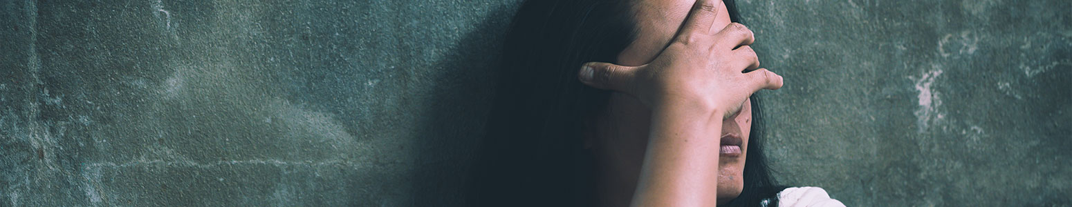 girl covering face against green wall