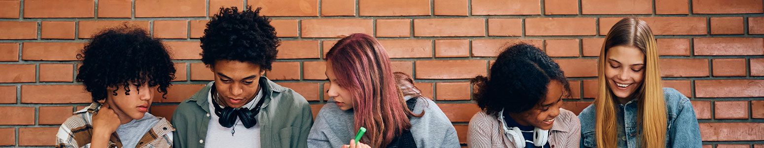 group of friends socializing against brick wall